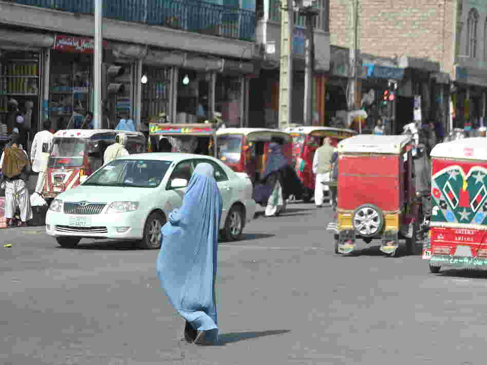 A woman crosses the street in Herat, Afghanistan. Burqa-clad women stand out on the streets in Afghanistan â both because of their bright blue burqas, and because there are far fewer women in public than men. A woman crosses the street in Herat, Afghanistan. Burqa-clad women stand out on the streets in Afghanistan â both because of their bright blue burqas, and because there are far fewer women in public than men.