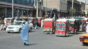 A woman crosses the street in Herat, Afghanistan. Burqa-clad women stand out on the streets in Afghanistan â both because of their bright blue burqas, and because there are far fewer women in public than men.
