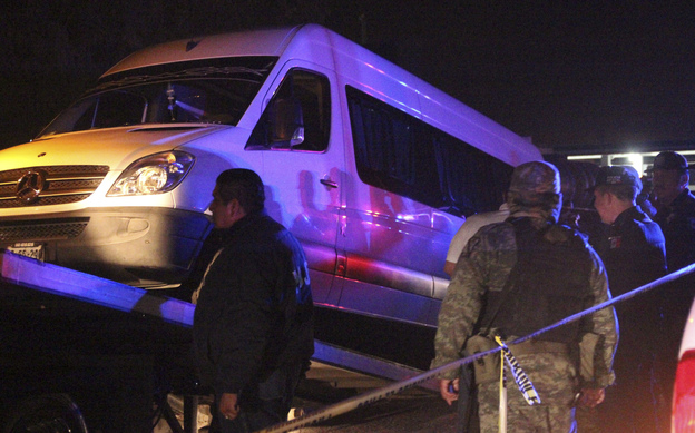 Police officers and soldiers stand around a white van containing the dead bodies of several man while it is being hauled onto a tow truck in San Luis Potosi on Thursday.