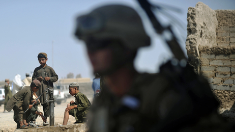 As boys washed their feet in the background, a U.S. Marine stood nearby earlier this summer in Helmand Province, Afghanistan. As boys washed their feet in the background, a U.S. Marine stood nearby earlier this summer in Helmand Province, Afghanistan.