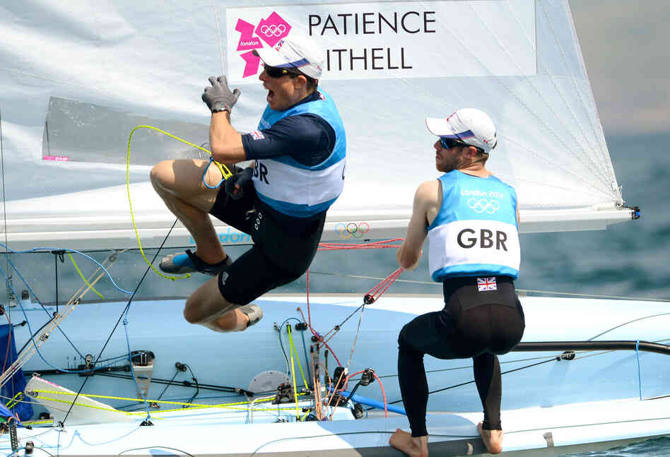 Great Britain's Stuart Bithell leaps off the boat while teammate Luke Patience sails on as they win silver in the men's sailing 470 two-person dinghy medal race in Weymouth, England.