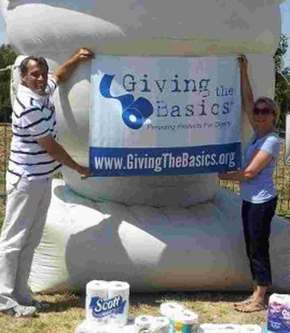 Tim Bair and Theresa Hamilton hoist a Giving the Basics banner. Tim Bair and Theresa Hamilton hoist a Giving the Basics banner.