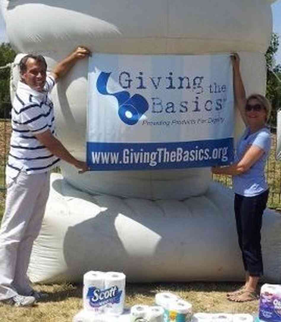 Tim Bair and Theresa Hamilton hoist a Giving the Basics banner. Tim Bair and Theresa Hamilton hoist a Giving the Basics banner.