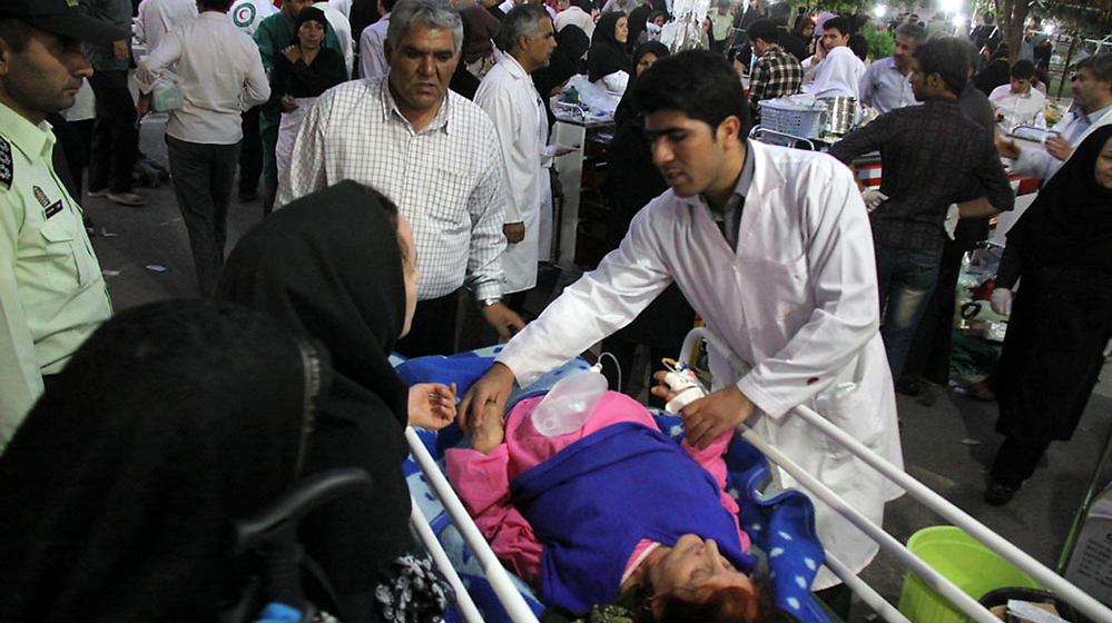 A medic attends to an injured woman as people gather outside a hospital in Ahar, Iran, after a strong earthquake hit northwestern part of the country Saturday.