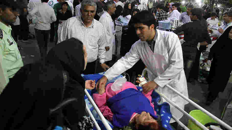 A medic attends to an injured woman as people gather outside a hospital in Ahar, Iran, after a strong earthquake hit northwestern part of the country Saturday.