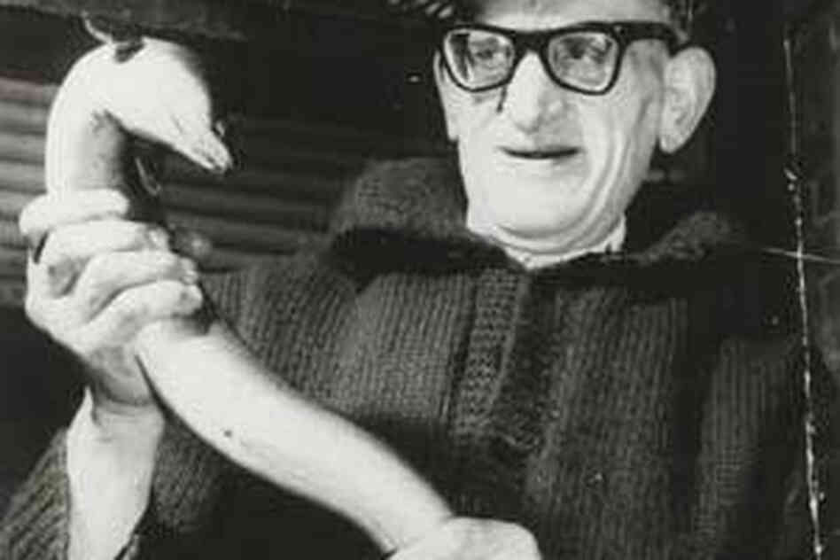 George Kelly of G. Kelly Pie and Mash Shop holds an eel in this undated photo on the wall at F. Cooke's.