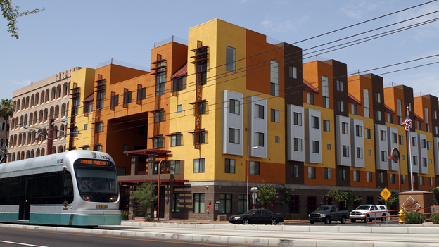 A Metro Light Rail train rolls by the Devine Legacy apartment building along Central Avenue in Phoenix. The energy-efficient complex includes 65 