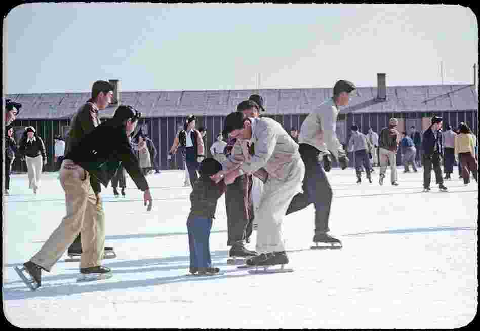 Photographer Bill Manbo's son Billy (center) gets a lesson in ice skating. Internees at Heart Mountain used fire hoses to create skating rinks around the camp during winter months.