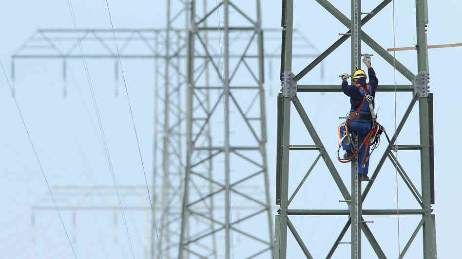 A worker on a newly constructed transmission tower near Buetzow, Germany, earlier this month. The German government plans to shut down nuclear power plants and is seeking to replace that production with power from renewable energy sources, especially wind turbines and solar parks. New power transmission lines will be needed. A worker on a newly constructed transmission tower near Buetzow, Germany, earlier this month. The German government plans to shut down nuclear power plants and is seeking to replace that production with power from renewable energy sources, especially wind turbines and solar parks. New power transmission lines will be needed.