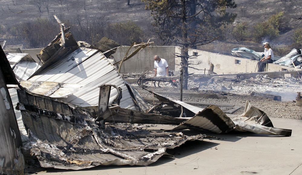 As embers still smolder, family members sift through the remains of their home that was destroyed in a wildfire.
