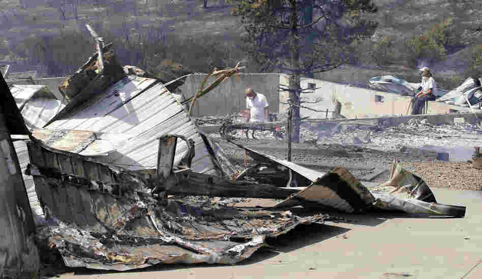 As embers still smolder, family members sift through the remains of their home that was destroyed in a wildfire.
