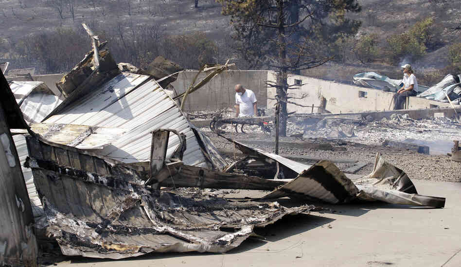 As embers still smolder, family members sift through the remains of their home that was destroyed in a wildfire.
