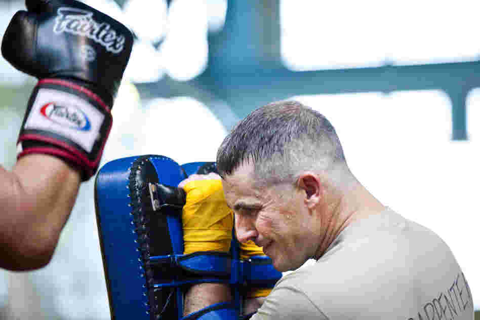 Maj. Christopher Carpenter takes a series of kicks and punches from a sparring partner. The soldiers take turns holding pads and practicing kicking and punching combos that will help them in close combat situations.