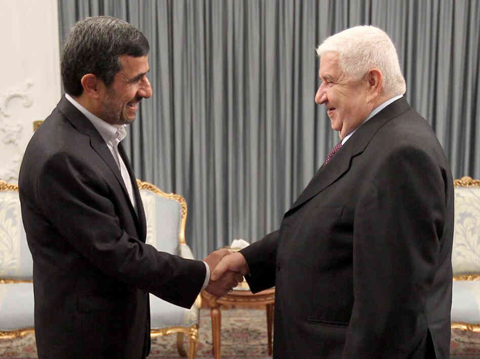 Iranian President Mahmoud Ahmadinejad (left) greets Syrian Foreign Minister Walid al-Muallem in the presidential palace in Tehran on July 29, in this official handout photo. The war in Syria threatens Iran's only ally in the Arab world.