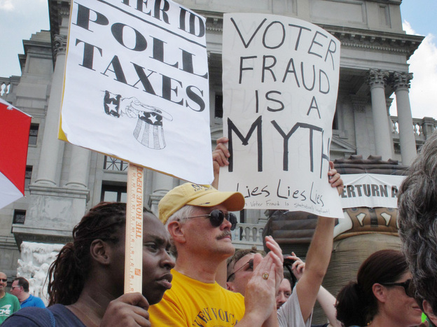 Demonstrators hold signs at an NAACP-organized rally on the steps of the Pennsylvania Capitol to protest the state's new voter identification law on July 24 in Harrisburg, Pa.