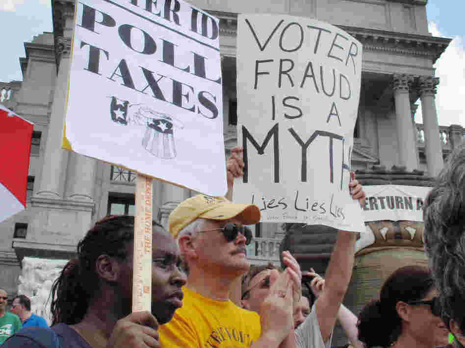 Demonstrators hold signs at an NAACP-organized rally on the steps of the Pennsylvania Capitol to protest the state's new voter identification law on July 24 in Harrisburg, Pa.