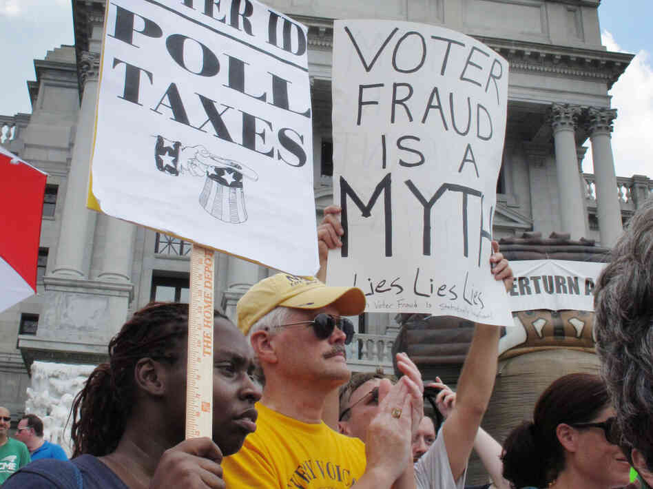 Demonstrators hold signs at an NAACP-organized rally on the steps of the Pennsylvania Capitol to protest the state's new voter identification law on July 24 in Harrisburg, Pa.