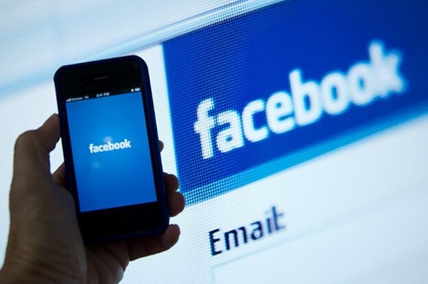 An illustration of an Apple iPhone displaying the Facebook app's splash screen in front of the login page.