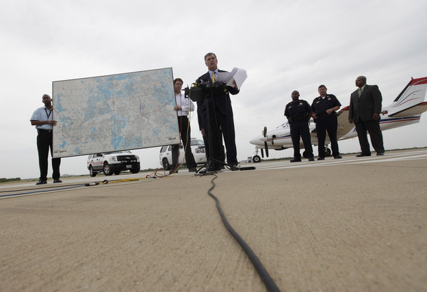 Dallas Mayor Mike Rawlings, center, holds a news conference in front of a plane that will be used for aerial spraying in Dallas.