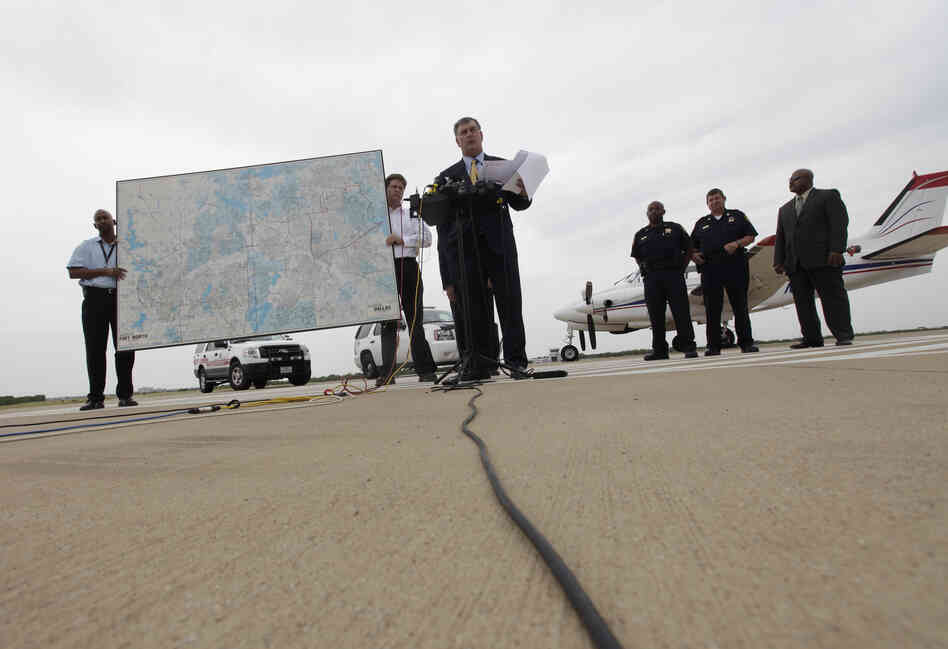Dallas Mayor Mike Rawlings, center, holds a news conference in front of a plane that will be used for aerial spraying in Dallas.