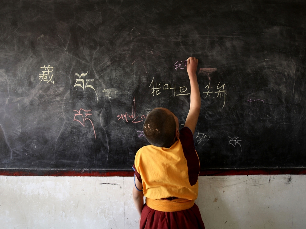 A lama student writes Chinese characters on a blackboard during a class on November 1, 2007 in Dari County of Guoluo Prefecture, Qinghai Province, northwest China.