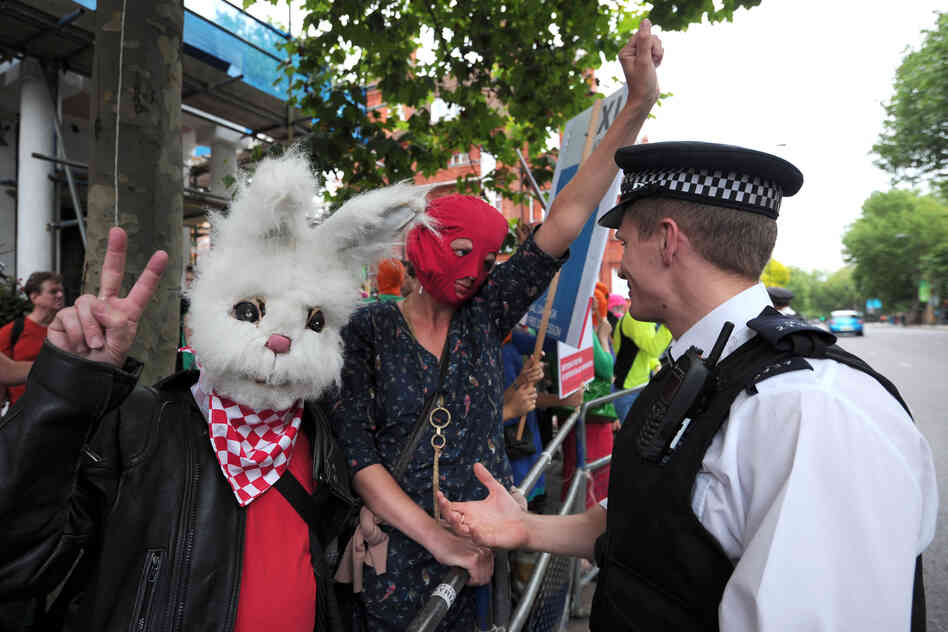 A police officer talks with London protesters.