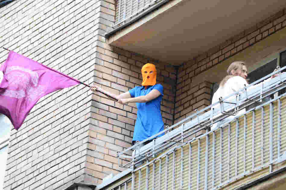 A supporter of feminist punk band Pussy Riot, wearing the group's trademark colored balaclava, waves a flag on a balcony in Moscow on Friday.