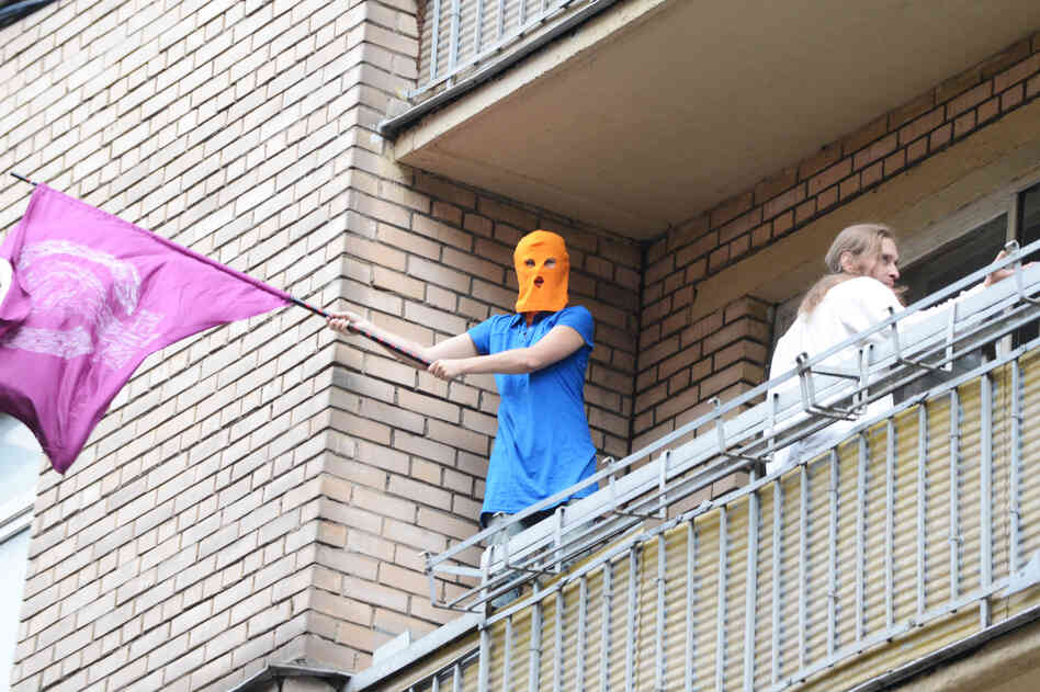 A supporter of feminist punk band Pussy Riot, wearing the group's trademark colored balaclava, waves a flag on a balcony in Moscow on Friday.