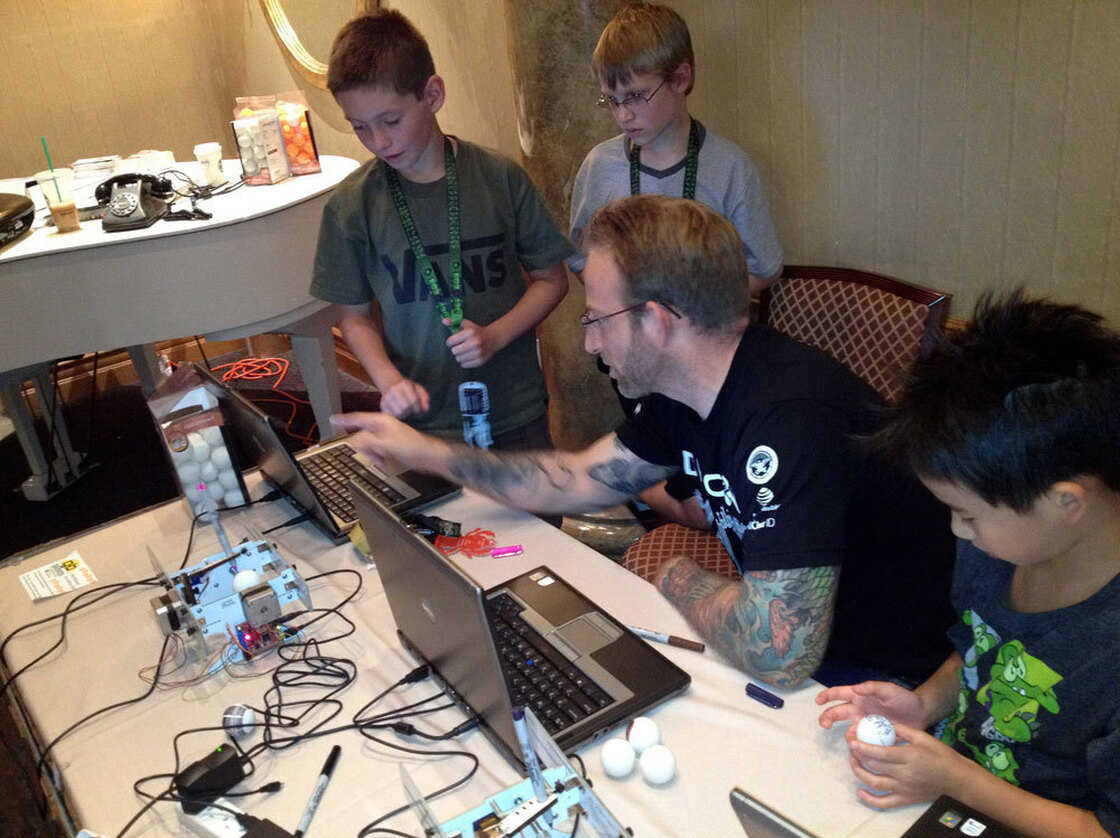 DefCon Kids camp co-founder Chris Hoff, with Conner Gilliam (from left), Conner Fine and Ethan Lai, work on a machine that draws designs on ping-pong balls. The camp is held in Las Vegas.