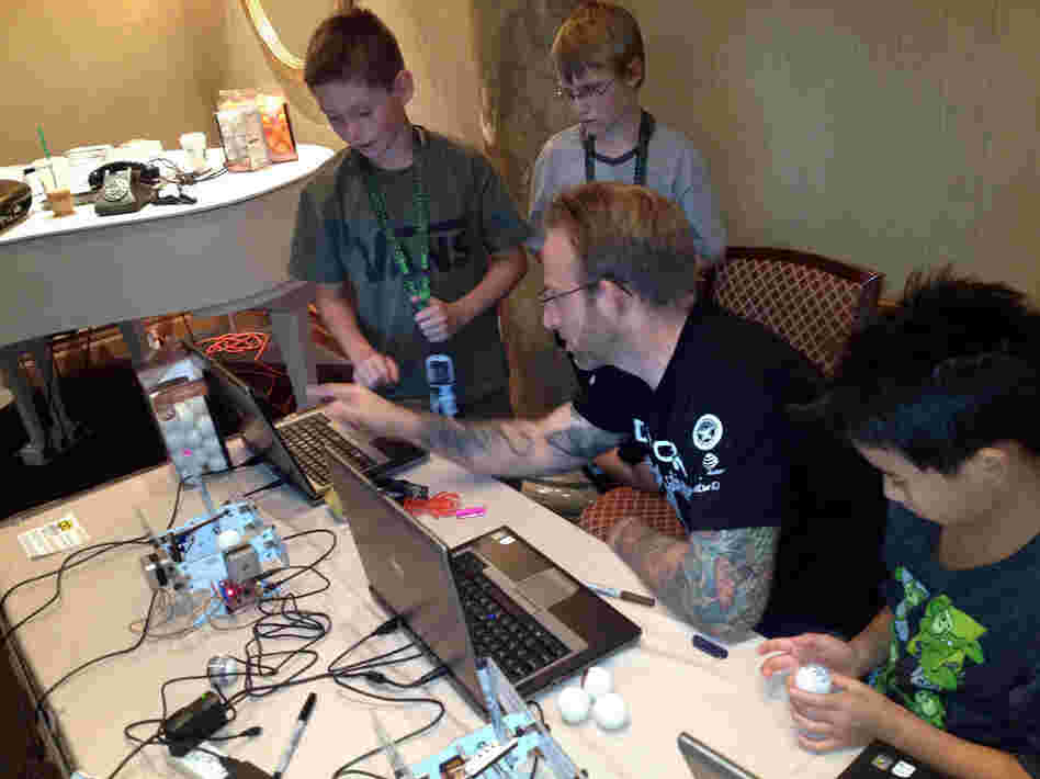 DefCon Kids camp co-founder Chris Hoff, with Conner Gilliam (from left), Conner Fine and Ethan Lai, work on a machine that draws designs on ping-pong balls. The camp is held in Las Vegas.