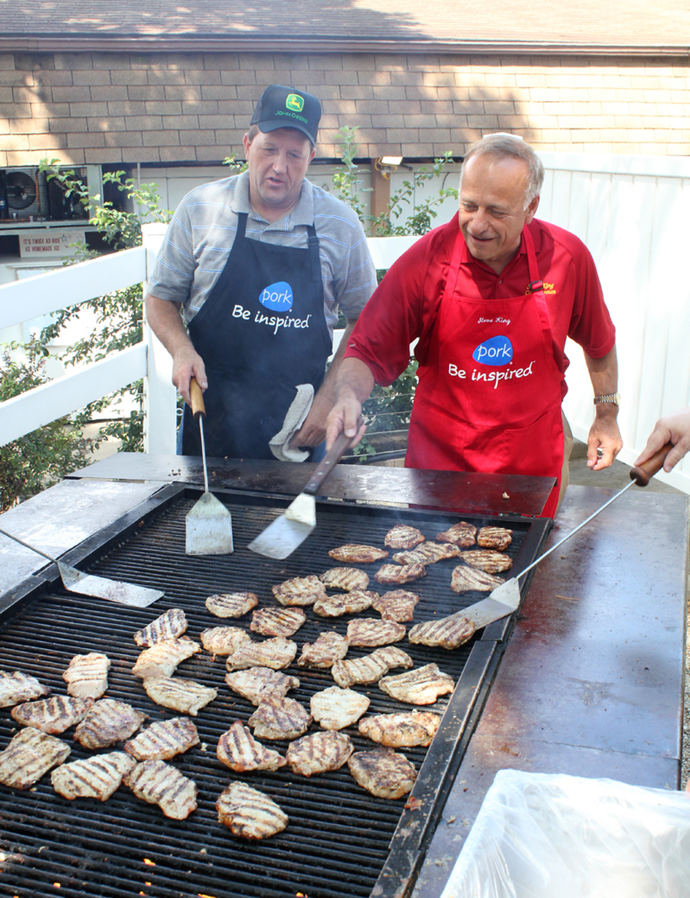 Republican Rep. Steve King of Iowa (right) flips pork chops at the Iowa State Fair in Des Moines while Terry Aupperle of Wiota watches. Aupperle lives in Cass County. He can't vote for King anymore because of redistricting.