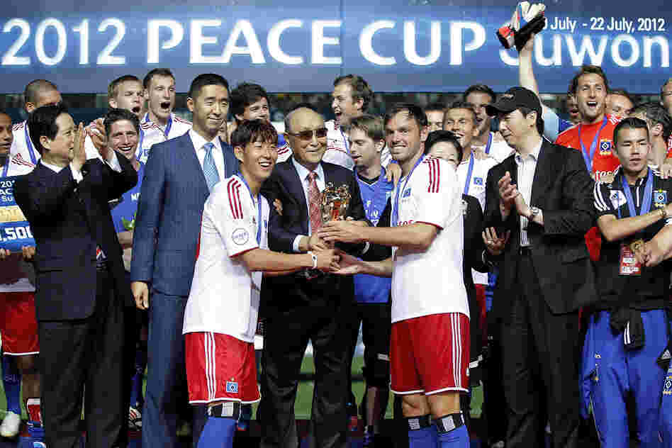 Captain Heiko Westermann (third right) and Son Heung-Min (third left) of Hamburger hold the trophy with Moon, as they celebrate after winning the Peace Cup final match.