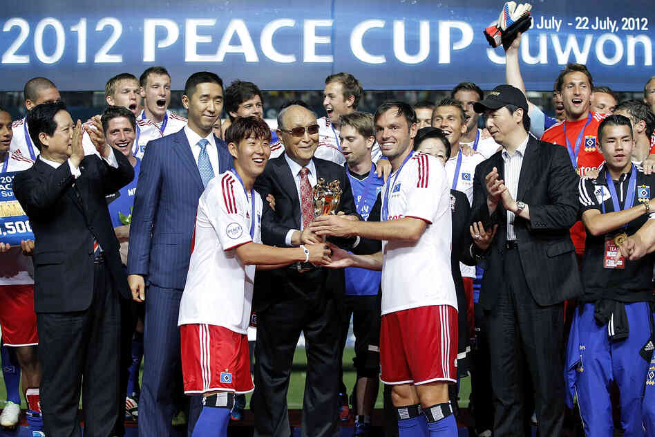 Captain Heiko Westermann (third right) and Son Heung-Min (third left) of Hamburger hold the trophy with Moon, as they celebrate after winning the Peace Cup final match.