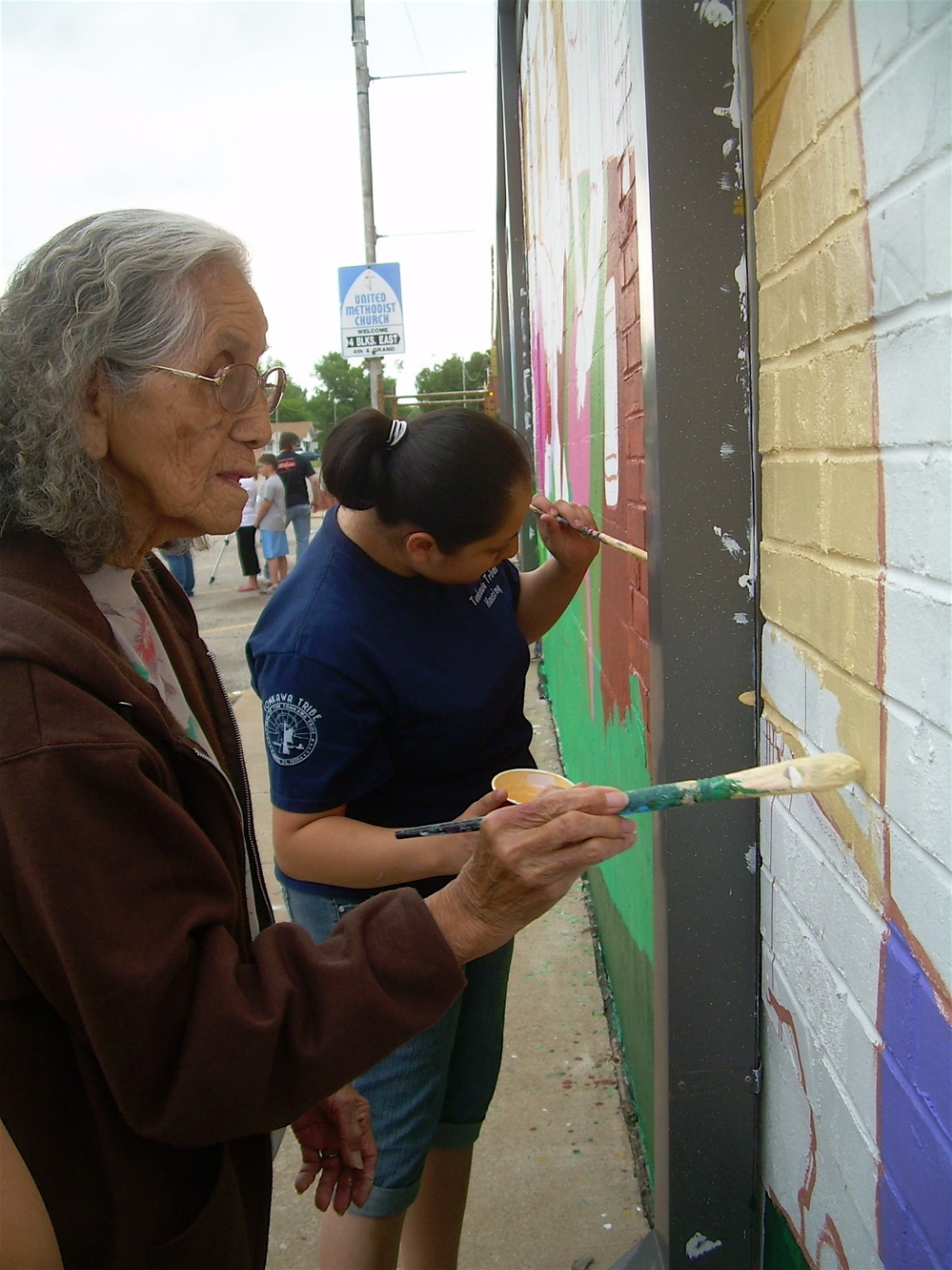 Tonkawa Tribal members add paint to the mural in Oklahoma.