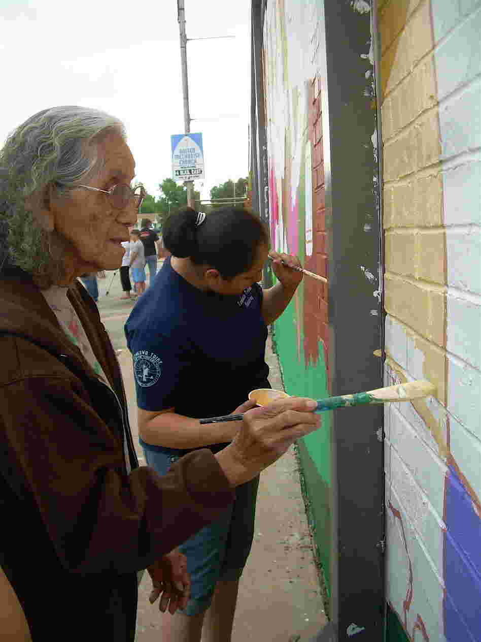 Tonkawa Tribal members add paint to the mural in Oklahoma.