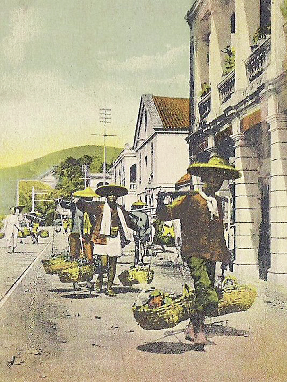 Hawkers carry goods for sale along the street in early Hong Kong.