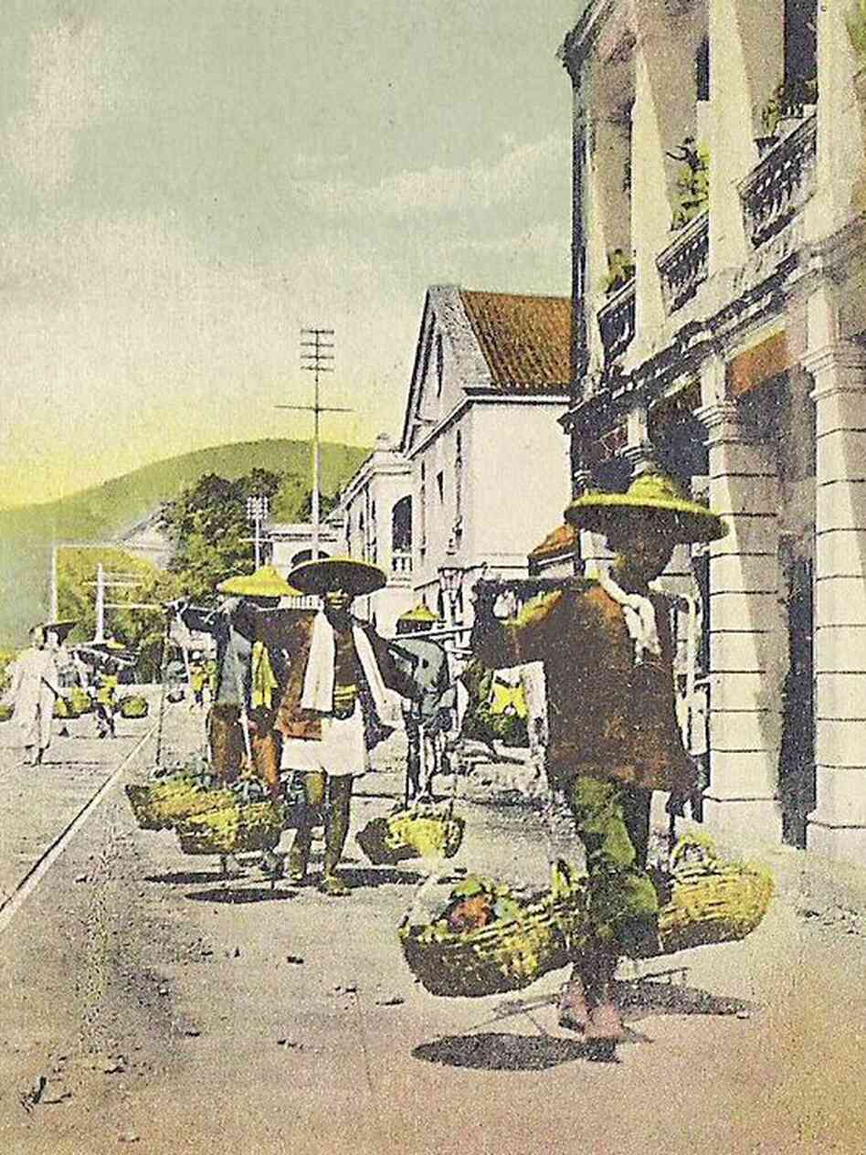 Hawkers carry goods for sale along the street in early Hong Kong.
