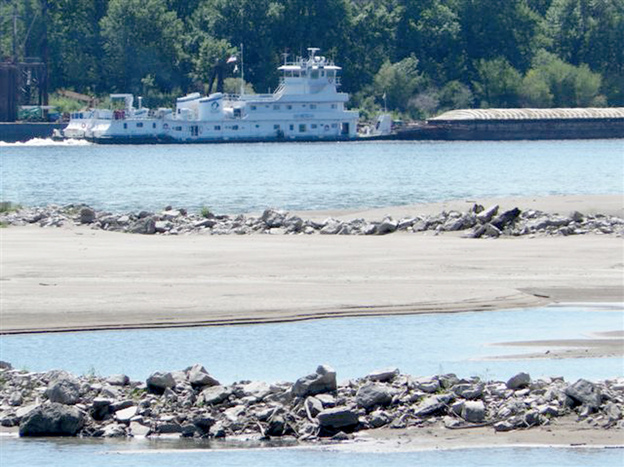 A tow pushes a barge past a sandbar on the Mississippi River near the confluence with the Missouri River north of St. Louis., on Friday. Many sandbars normally under water on the two rivers are now exposed as the drought has caused river levels to drop.