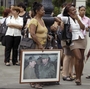 People, one holding an image of Cuba's President Raul Castro  and his brother Fidel Castro, wait in line at a bus stop in Havana last month.