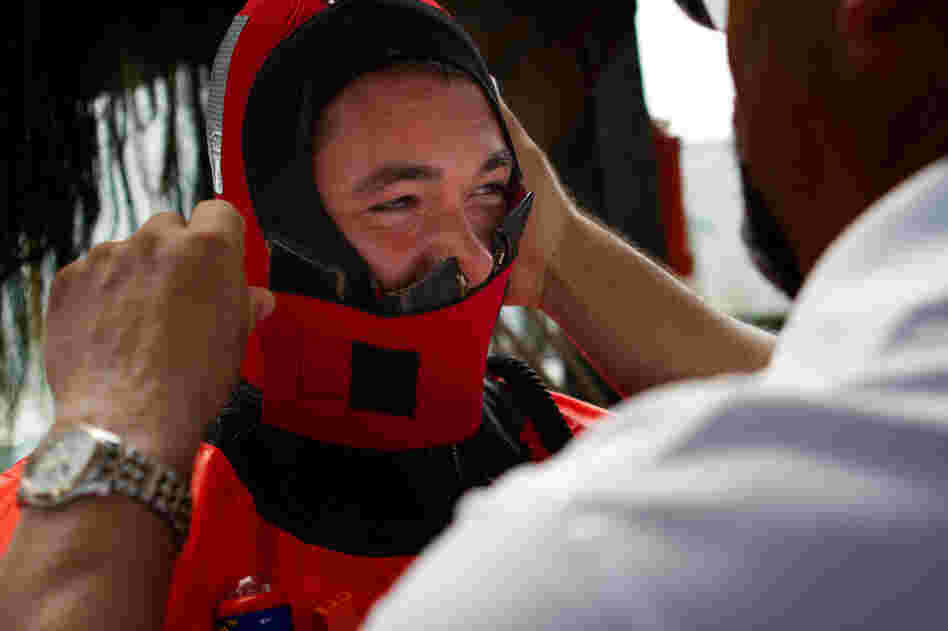 Aboard the Debbie Ann, training instructor Fred Mattera helps a fisherman zip up a survival suit as part of an abandon-ship exercise in Point Judith, R.I.