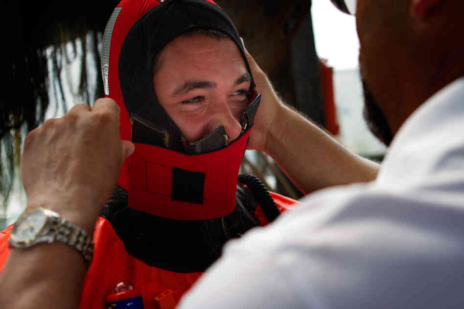 Aboard the Debbie Ann, training instructor Fred Mattera helps a fisherman zip up a survival suit as part of an abandon-ship exercise in Point Judith, R.I.