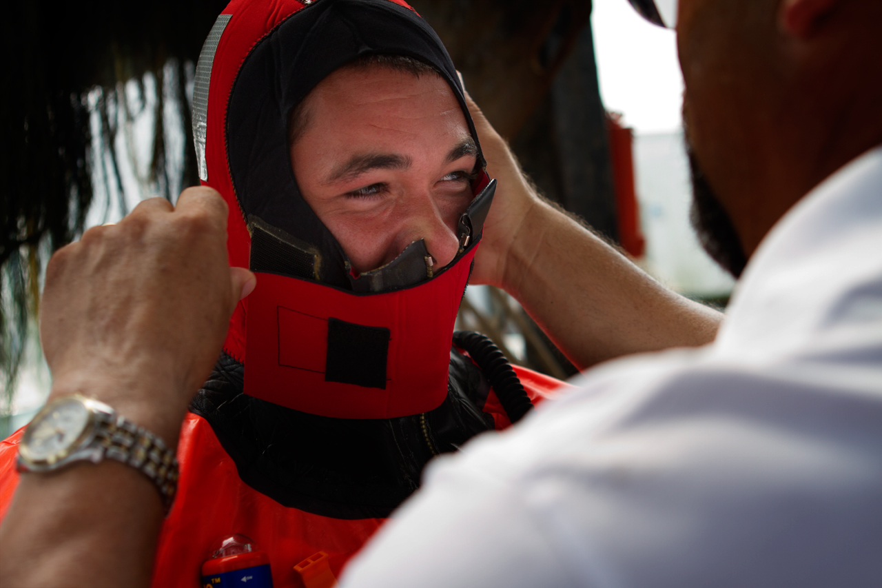 Aboard the Debbie Ann, training instructor Fred Mattera helps a fisherman zip up a survival suit as part of an abandon-ship exercise in Point Judith, R.I.