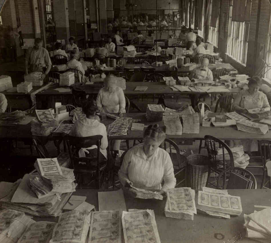 Workers inspecting sheets of money for printing flaws and smudges, circa 1917. Approved sheets received serial numbers and U.S. Treasury seals. Workers inspecting sheets of money for printing flaws and smudges, circa 1917. Approved sheets received serial numbers and U.S. Treasury seals.