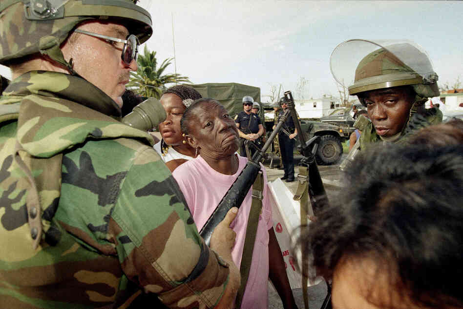 Florida National Guardsman Sgt. Jim Urbanik of Tampa holds out his gun to keep people in line as they wait for food at a distribution center in Florida City. Many residents of the south Dade County farming community lost their homes.