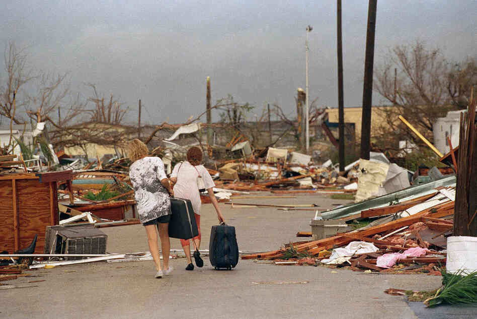Joan Wallach (left) and her daughter, Brenda, carry possessions they salvaged from their trailer as they walk through the debris that was the Royal Palm Trailer Court in Homestead.