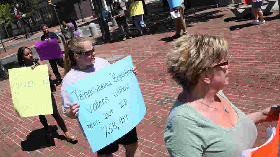Protesters hold signs in Allentown, Pa., om July 25 as the Commonwealth Court holds hearings on voter ID laws.