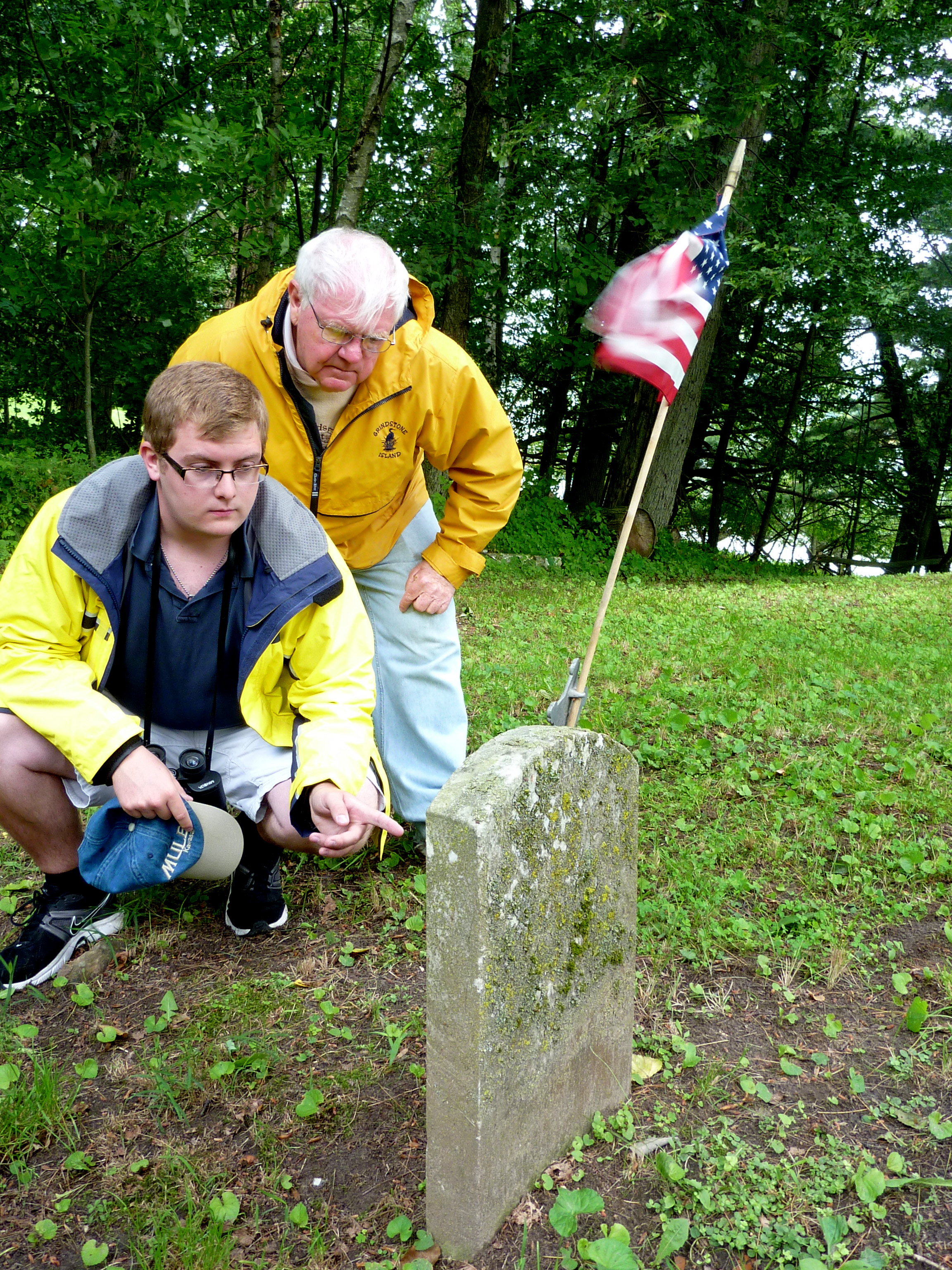 Jack Grobe (left) and Ken Deedy inspect a gravestone in one of Grindstone Island's unofficial cemeteries. Although he's only 19, Grobe says he'd like to be buried on the island someday.