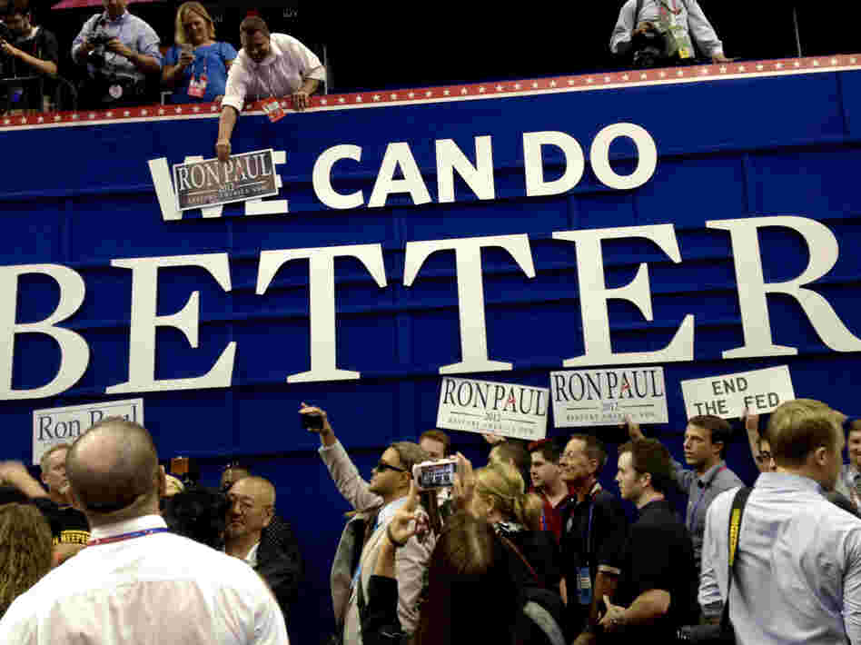 Ron Paul supporters pose with posters on the floor of the RNC on Monday in Tampa. They put "Ron Paul" over the word "We" on a GOP sign that says "We Can Do Better."
