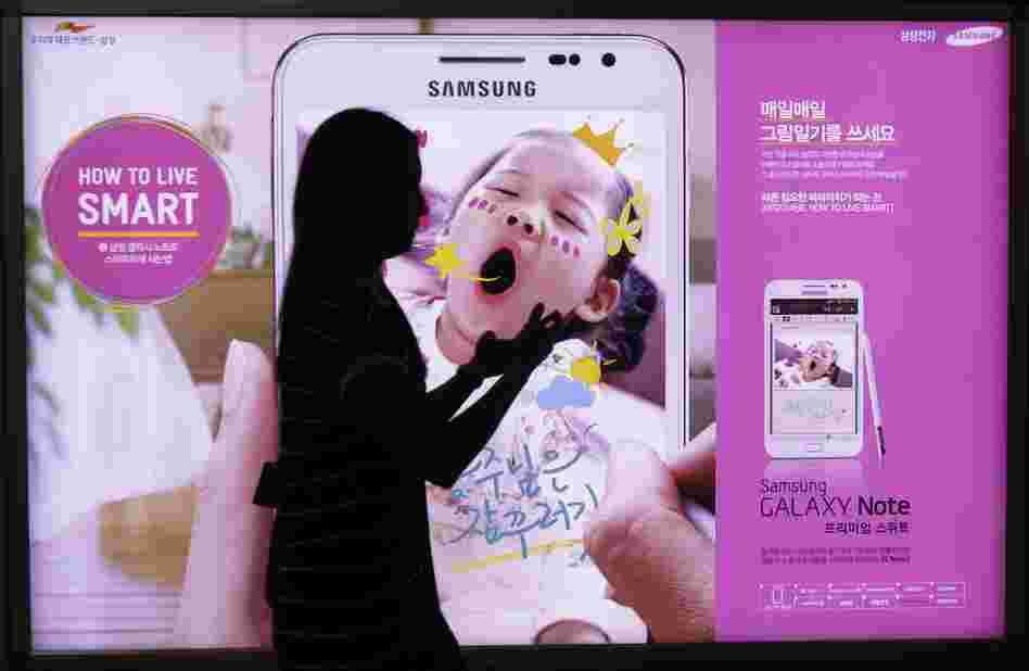 A woman walks across banner advertising for Samsung Electronics' Galaxy Note Seoul, South Korea on Monday.