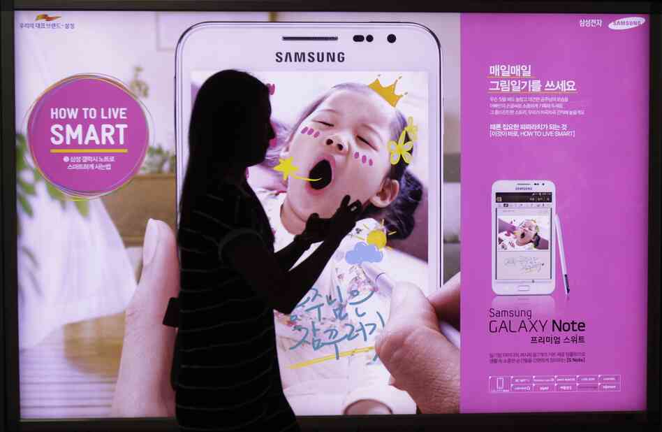 A woman walks across banner advertising for Samsung Electronics' Galaxy Note Seoul, South Korea on Monday.